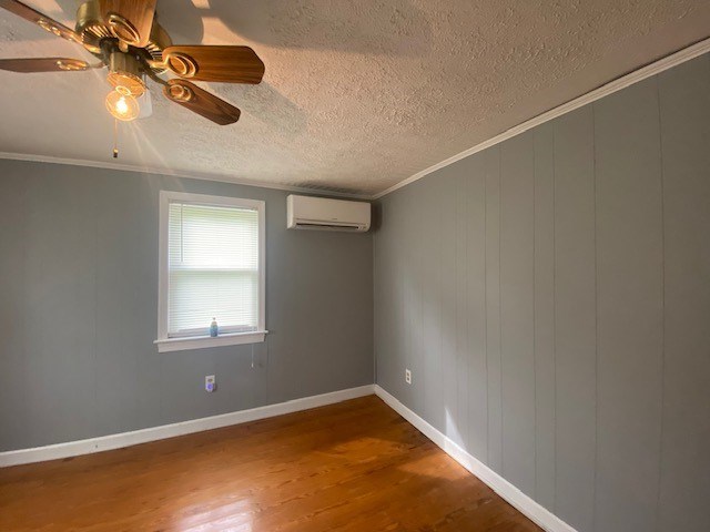 3097 Oakland Rd, Farnham, VA 22460 - empty room featuring a wall mounted AC, wood finished floors, crown molding, a ceiling fan, and a textured ceiling