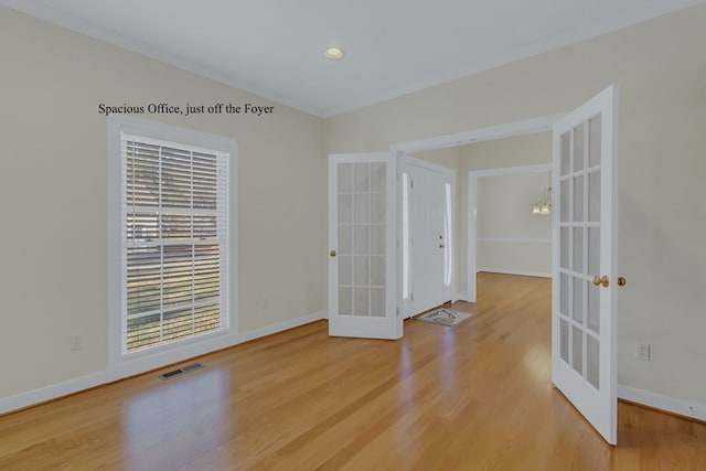 spare room with an inviting chandelier, wood-type flooring, ornamental molding, and french doors