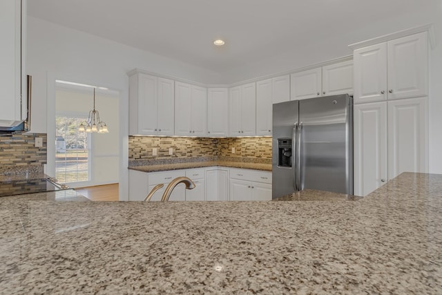 kitchen featuring white cabinets, sink, light stone countertops, and stainless steel refrigerator with ice dispenser