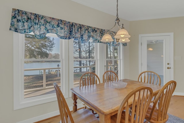 dining area featuring ceiling fan with notable chandelier, a water view, a wealth of natural light, and light hardwood / wood-style flooring