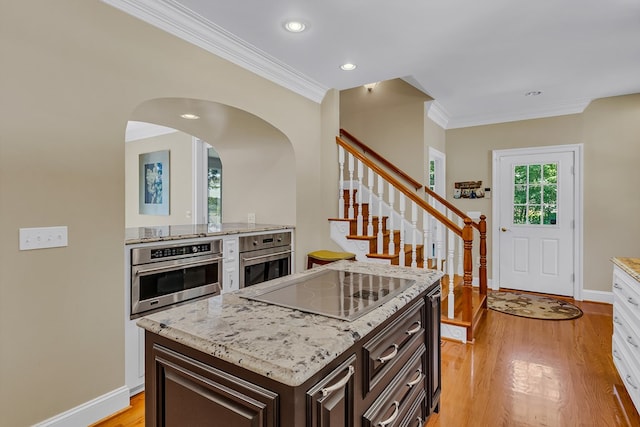 858 Harmony Hills Cir, Heathsville, VA 22473 - kitchen with stainless steel oven, black electric stovetop, ornamental molding, light wood finished floors, and dark brown cabinets