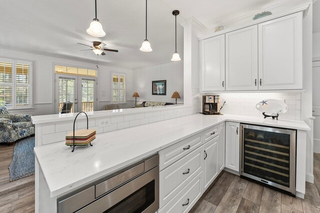 kitchen with wood finished floors, a peninsula, wine cooler, french doors, and white cabinetry