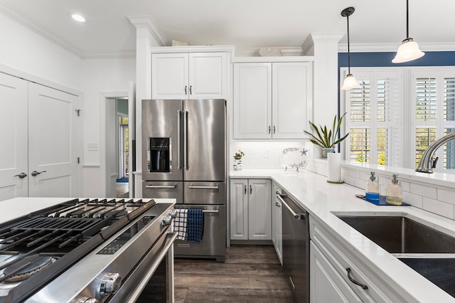 kitchen featuring a sink, backsplash, appliances with stainless steel finishes, crown molding, and hanging light fixtures