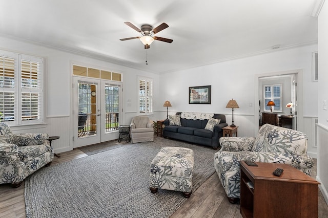 living area with french doors, wood finished floors, a healthy amount of sunlight, and a wainscoted wall