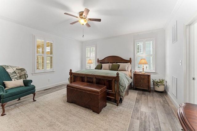 bedroom with light wood finished floors, visible vents, ceiling fan, baseboards, and ornamental molding