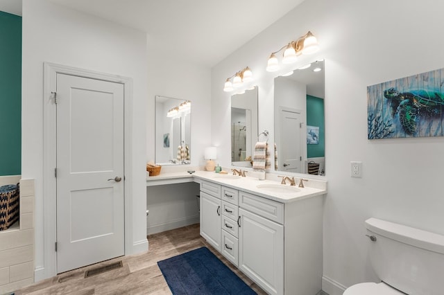 bathroom with double vanity, toilet, wood finished floors, and a sink