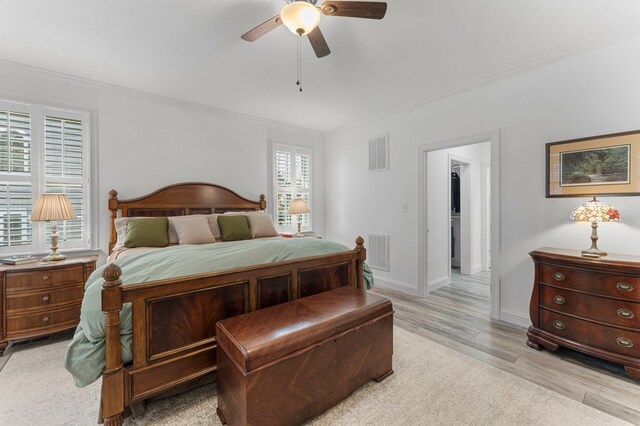 bedroom with light wood finished floors, visible vents, crown molding, and baseboards