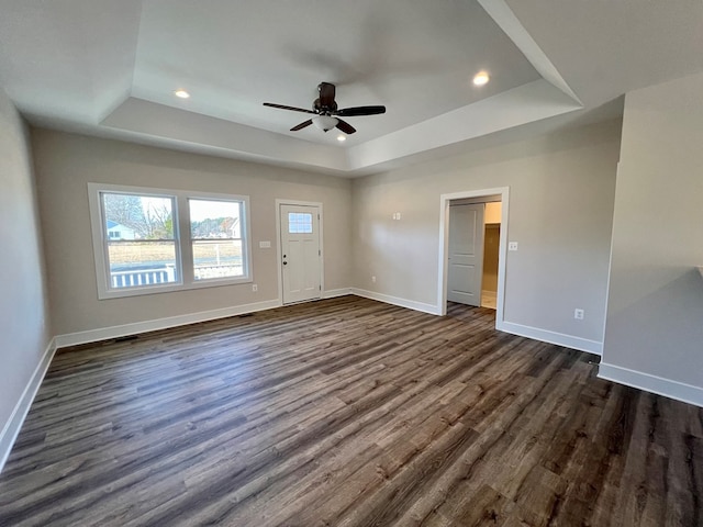 spare room with dark hardwood / wood-style floors, ceiling fan, and a tray ceiling