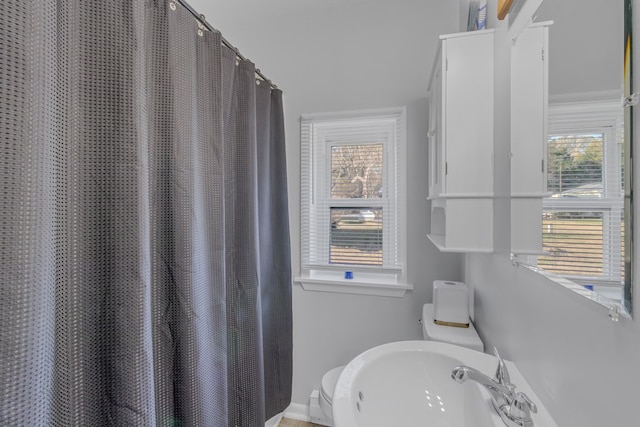 bathroom featuring a shower with shower curtain, toilet, and sink