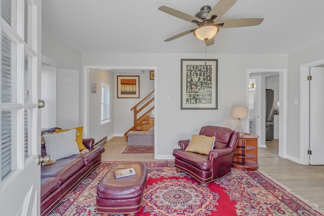 living room featuring ceiling fan, light hardwood / wood-style flooring, and a baseboard heating unit