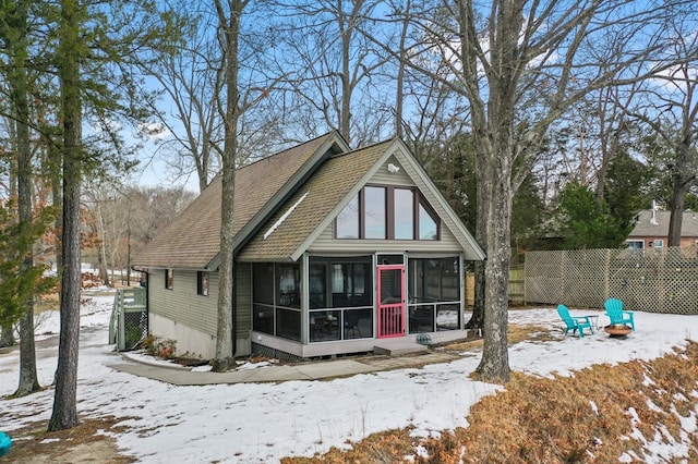 snow covered house featuring a sunroom and a fire pit