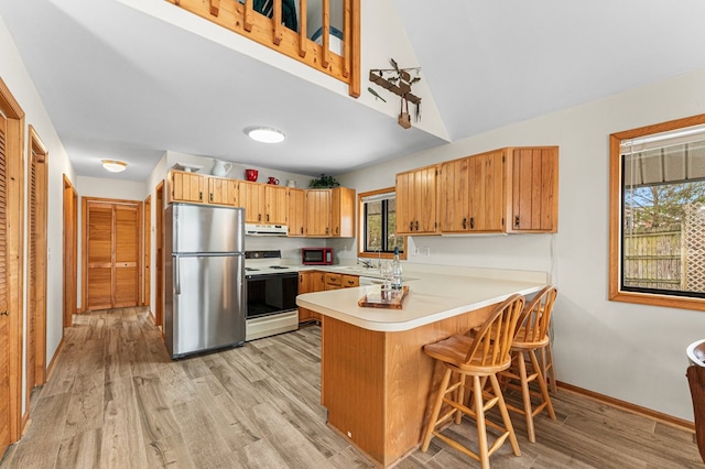 kitchen with electric stove, stainless steel fridge, light hardwood / wood-style flooring, and kitchen peninsula