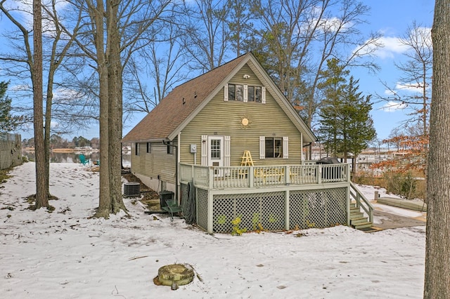 snow covered property with central air condition unit and a deck