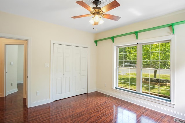 unfurnished bedroom featuring a closet, ceiling fan, and dark hardwood / wood-style flooring