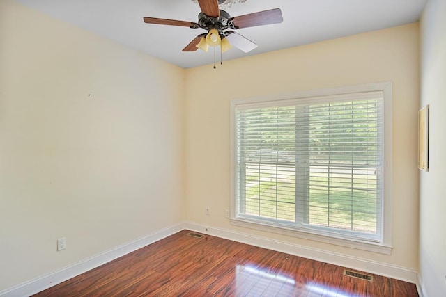 empty room with dark hardwood / wood-style floors, a wealth of natural light, and ceiling fan