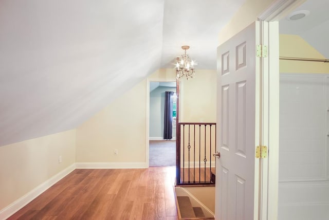 additional living space with wood-type flooring, lofted ceiling, and an inviting chandelier