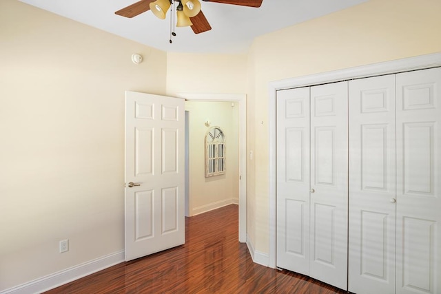 unfurnished bedroom featuring dark hardwood / wood-style flooring, ceiling fan, and a closet