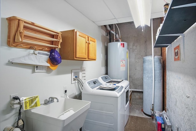 washroom featuring cabinets, sink, washer and dryer, and water heater