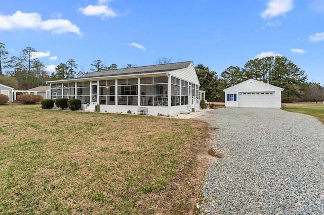 view of front of property featuring an outbuilding, a sunroom, a front yard, and a garage