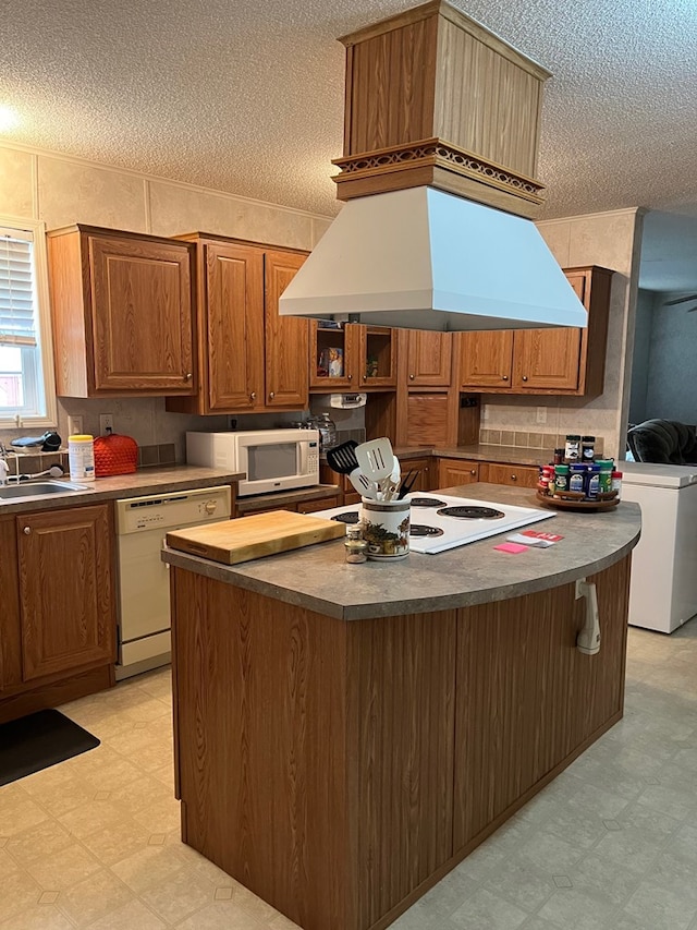 kitchen with sink, custom exhaust hood, a center island, a textured ceiling, and white appliances