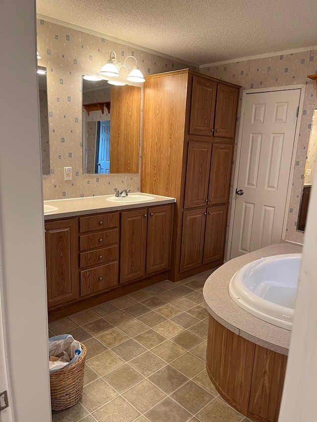 bathroom featuring vanity, a tub to relax in, ornamental molding, and a textured ceiling