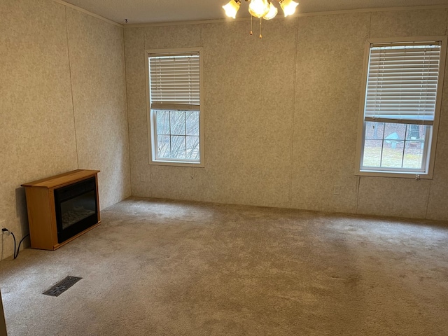 unfurnished living room with ornamental molding, carpet flooring, and a wealth of natural light