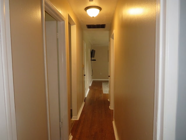 hall with a textured ceiling and dark wood-type flooring