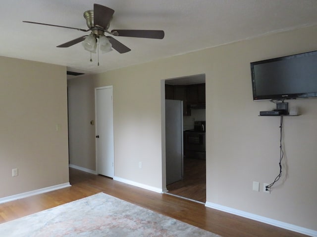 unfurnished bedroom featuring stainless steel fridge, ceiling fan, and hardwood / wood-style flooring