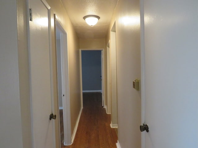 corridor featuring dark wood-type flooring and a textured ceiling