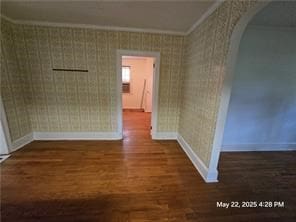 300 Irvington Rd, Kilmarnock, VA 22482 - empty room with baseboards, crown molding, wood finished floors, arched walkways, and wallpapered walls