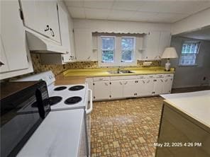 300 Irvington Rd, Kilmarnock, VA 22482 - kitchen with under cabinet range hood, white cabinetry, a sink, light countertops, and white range with electric cooktop