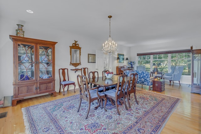 dining space with light wood-type flooring and a notable chandelier