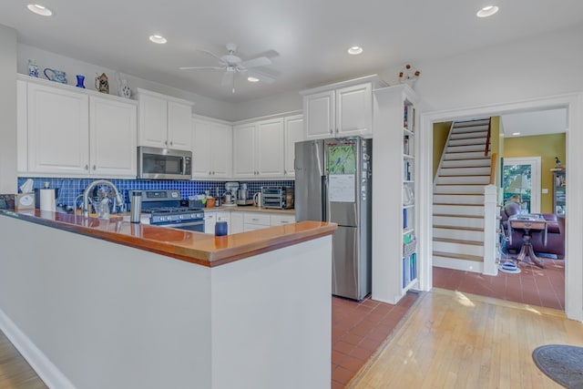 kitchen featuring white cabinetry, kitchen peninsula, appliances with stainless steel finishes, and tasteful backsplash