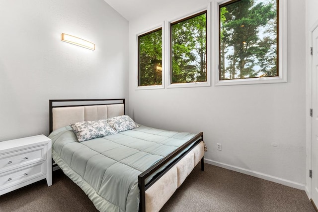 bedroom with dark colored carpet and baseboards