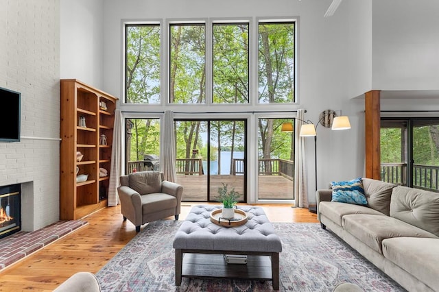 living area with plenty of natural light, a high ceiling, wood finished floors, and a fireplace