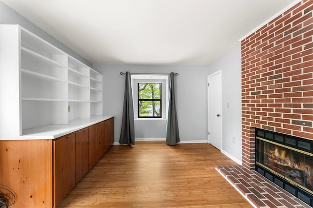 interior space with baseboards, a fireplace, and light wood-style flooring