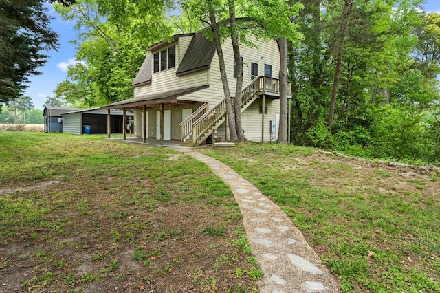 rear view of property featuring a wooden deck, a shingled roof, a lawn, stairs, and an attached garage