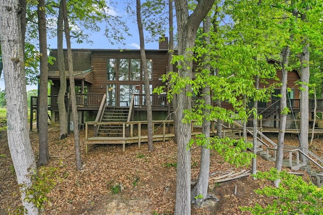 rear view of property featuring a chimney, stairway, and a wooden deck