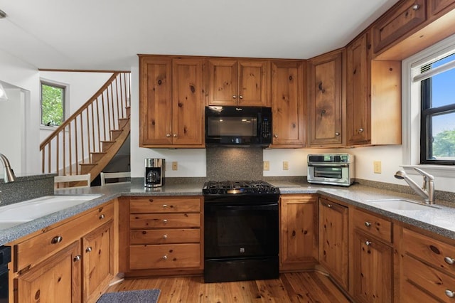 kitchen with brown cabinetry, black appliances, and a sink