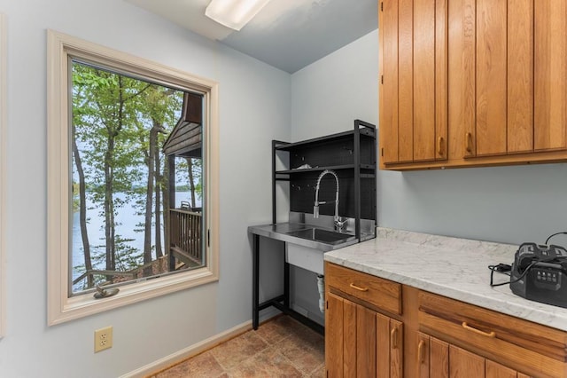kitchen with a sink, brown cabinets, baseboards, and a healthy amount of sunlight