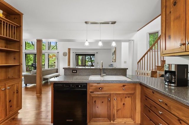 kitchen with wood finished floors, hanging light fixtures, brown cabinetry, black dishwasher, and a sink