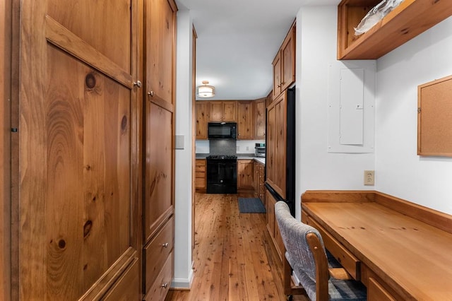 kitchen with black appliances, brown cabinets, electric panel, and light wood-style floors