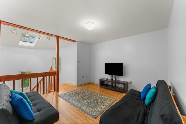 living area with a skylight, visible vents, and wood finished floors