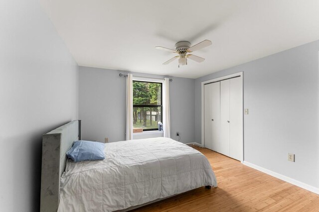 bedroom with a closet, a ceiling fan, wood finished floors, and baseboards