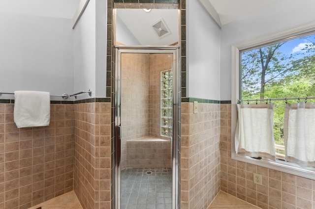 full bathroom featuring a stall shower, tile walls, a wainscoted wall, and tile patterned floors