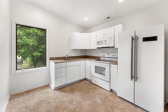 kitchen featuring white cabinets, a sink, dark countertops, visible vents, and white appliances