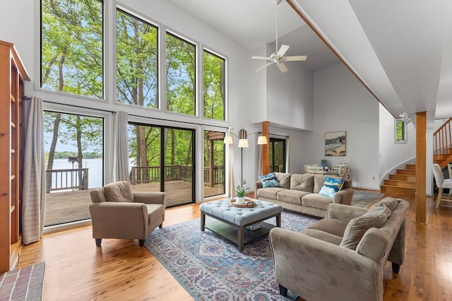 living room featuring a ceiling fan, high vaulted ceiling, stairway, and plenty of natural light