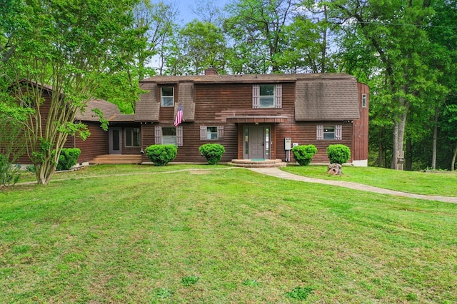 view of front of property featuring a front yard, a chimney, a gambrel roof, and roof with shingles