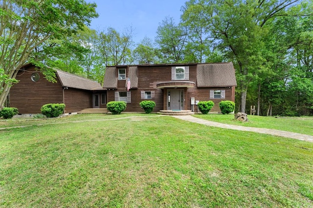 view of front of house with a front yard and a shingled roof