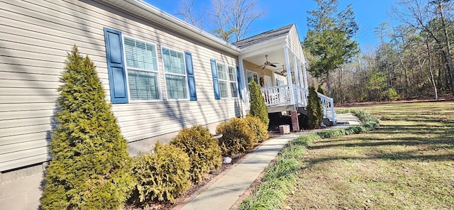 view of side of home with a lawn and ceiling fan